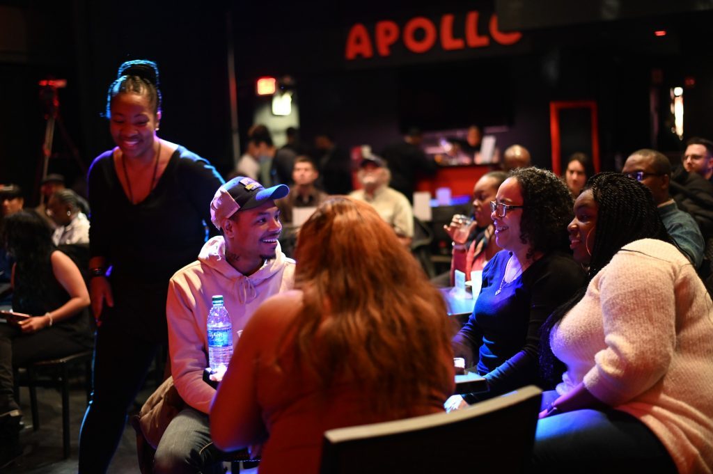 A group of people sitting around a table at Apollo Comedy Club