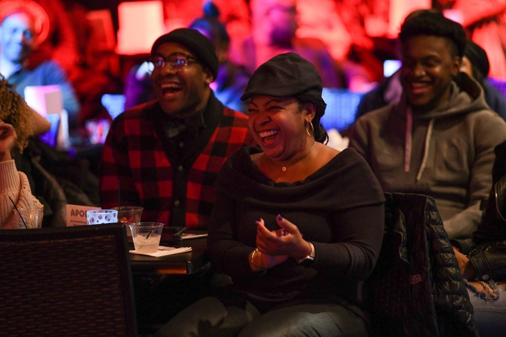 A woman with a hat on enjoying the Apollo Comedy Club
