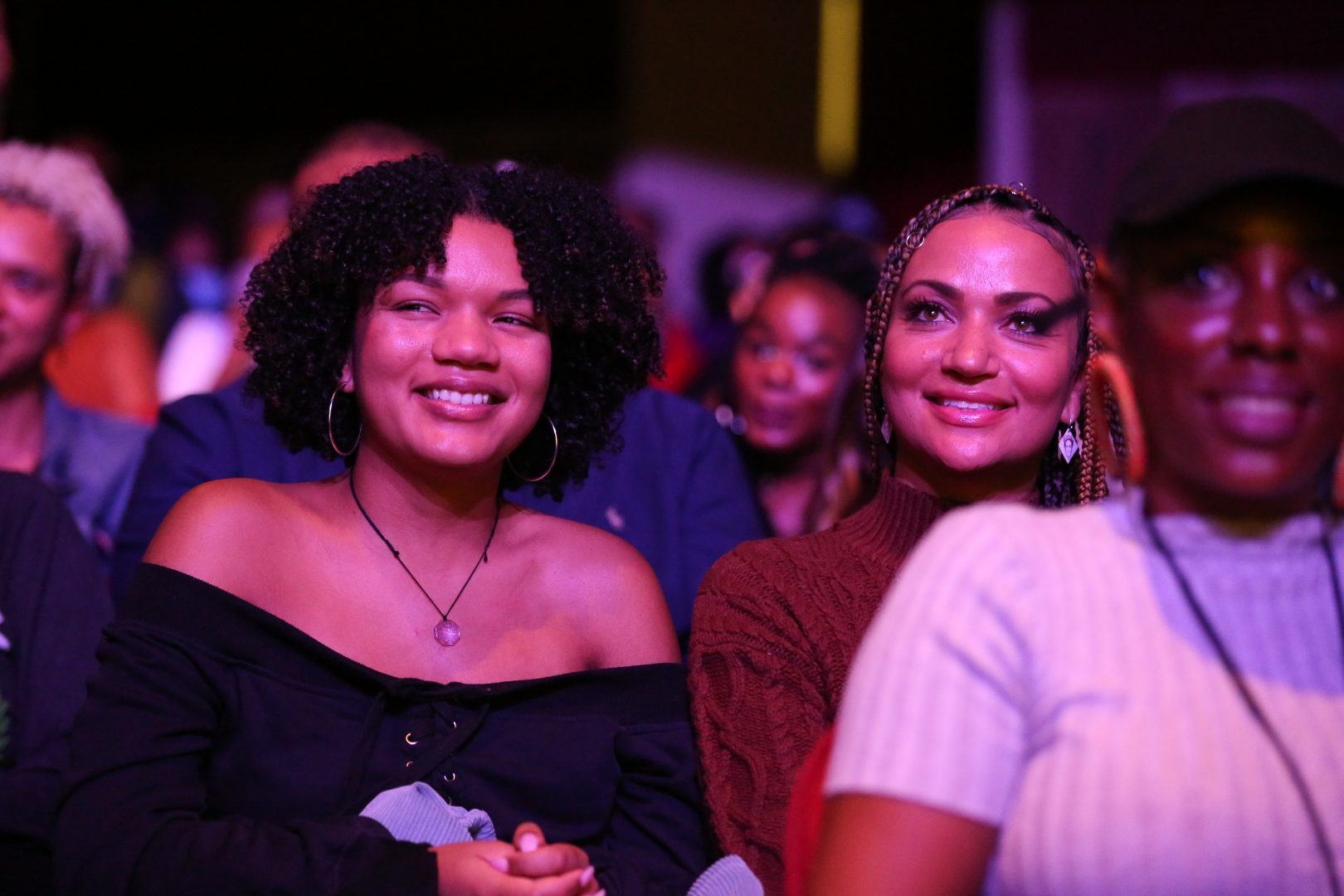 Two black women in the audience watching a performance at the Apollo