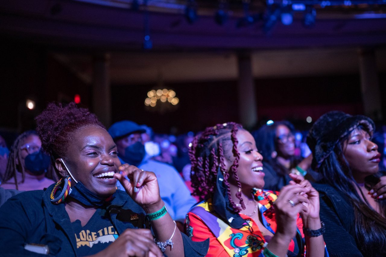 Two women smiling in the crowd during a performance at the Apollo