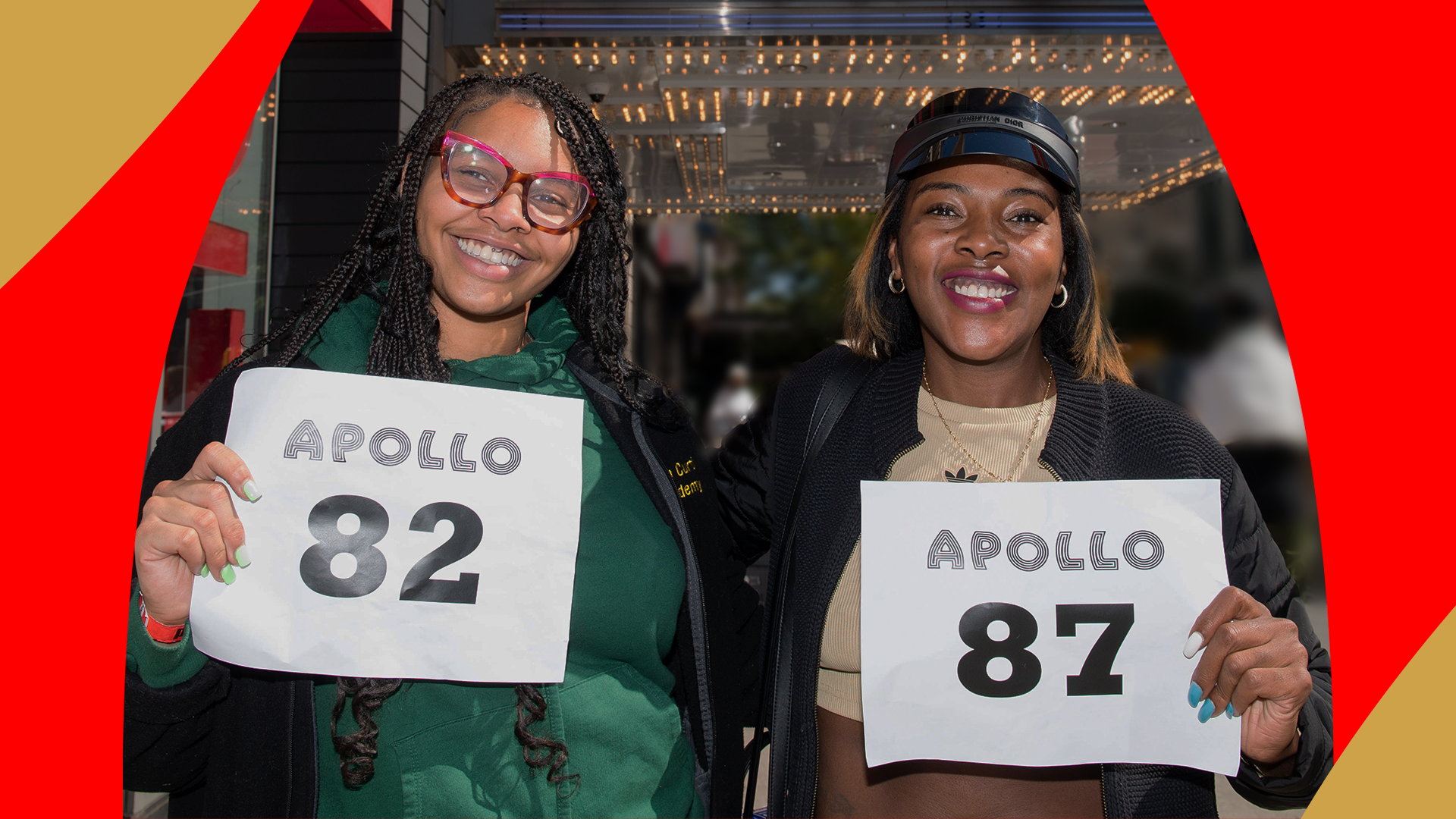 Two Amateur Night auditionees holding the numbers 82 and 87 respectively, in front of The Apollo's Legendary marquee