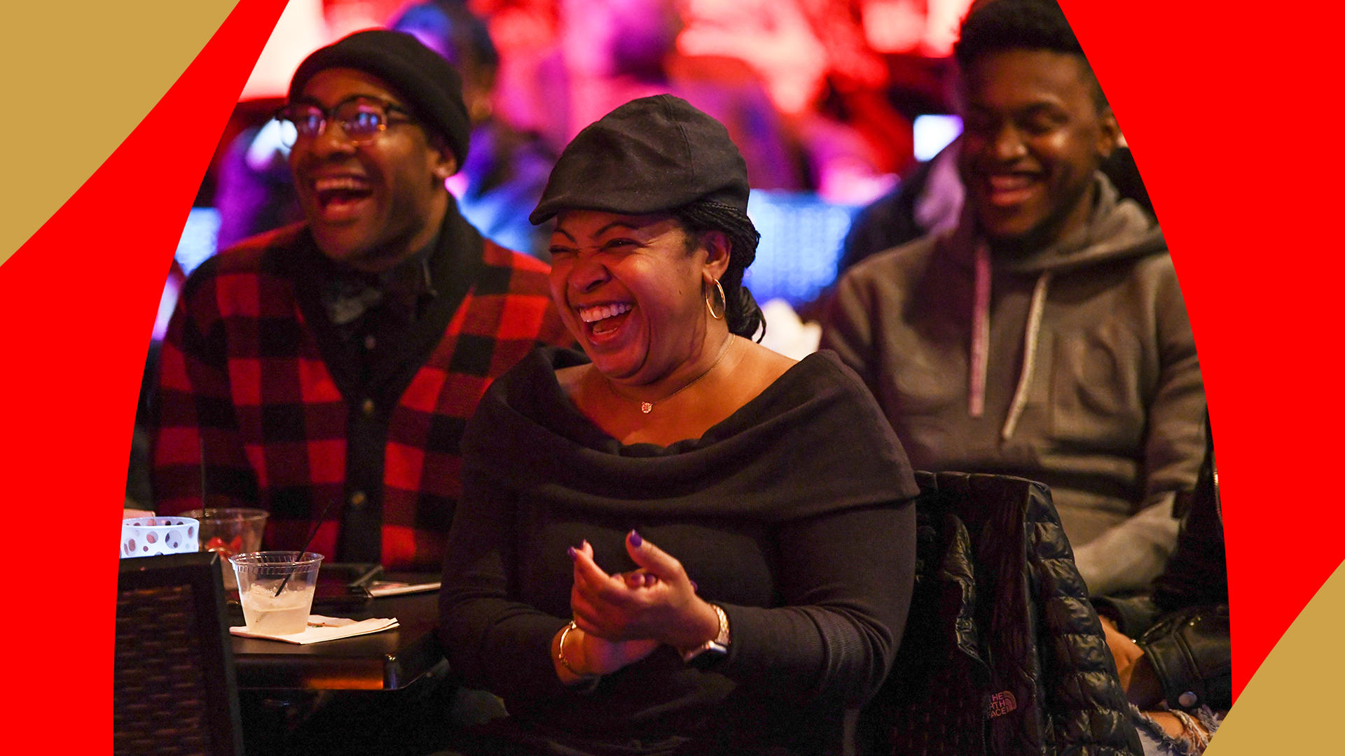 A group of three folks laughing sitting at Apollo Comedy Club tables.